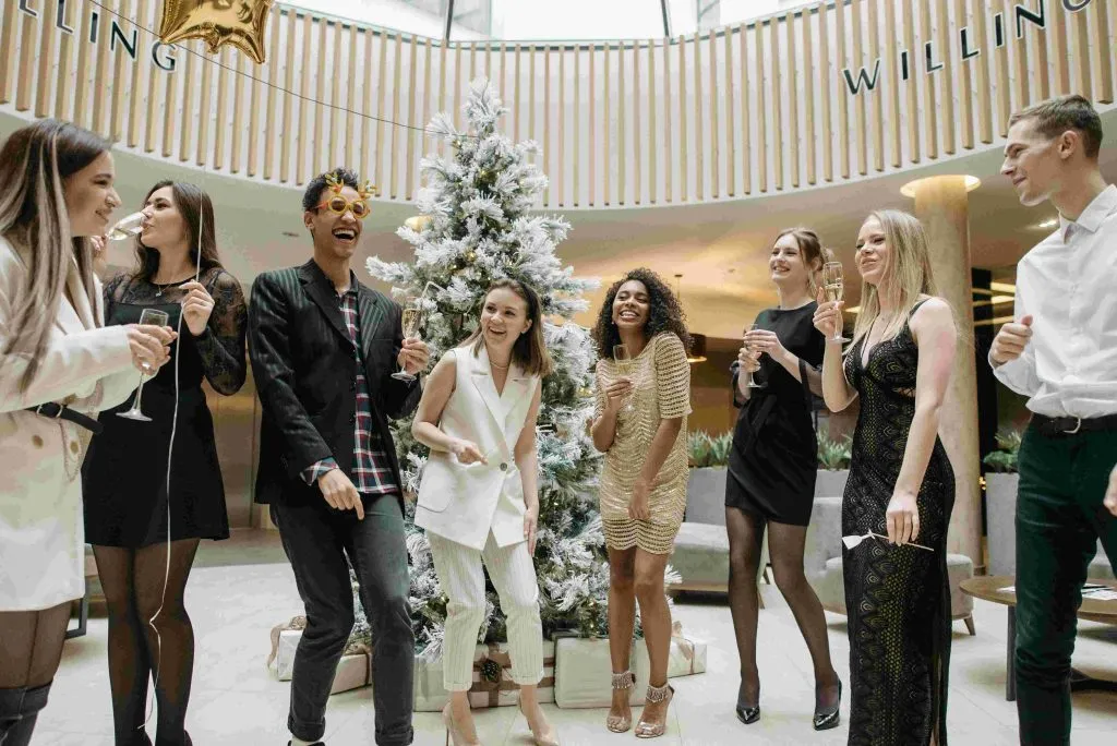 Compañeros brindando junto a un árbol de Navidad en la fiesta de empresa