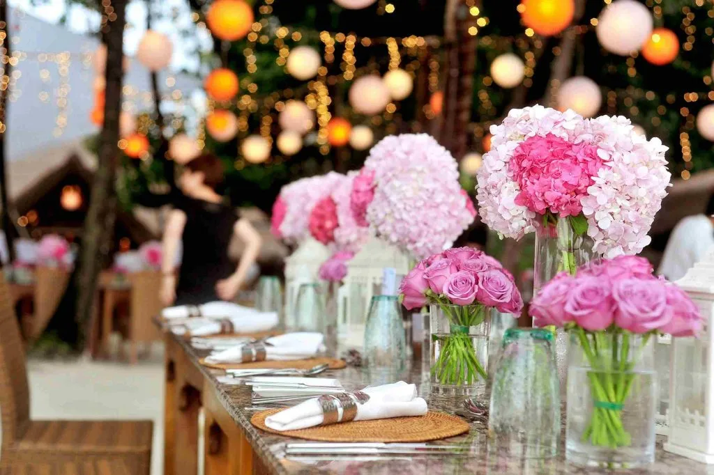 Mesa de boda al aire libre con hortensias rosas y farolillos