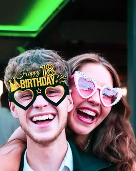 Dos invitados con gafas de fiesta posando en el fotomatón de un cumpleaños